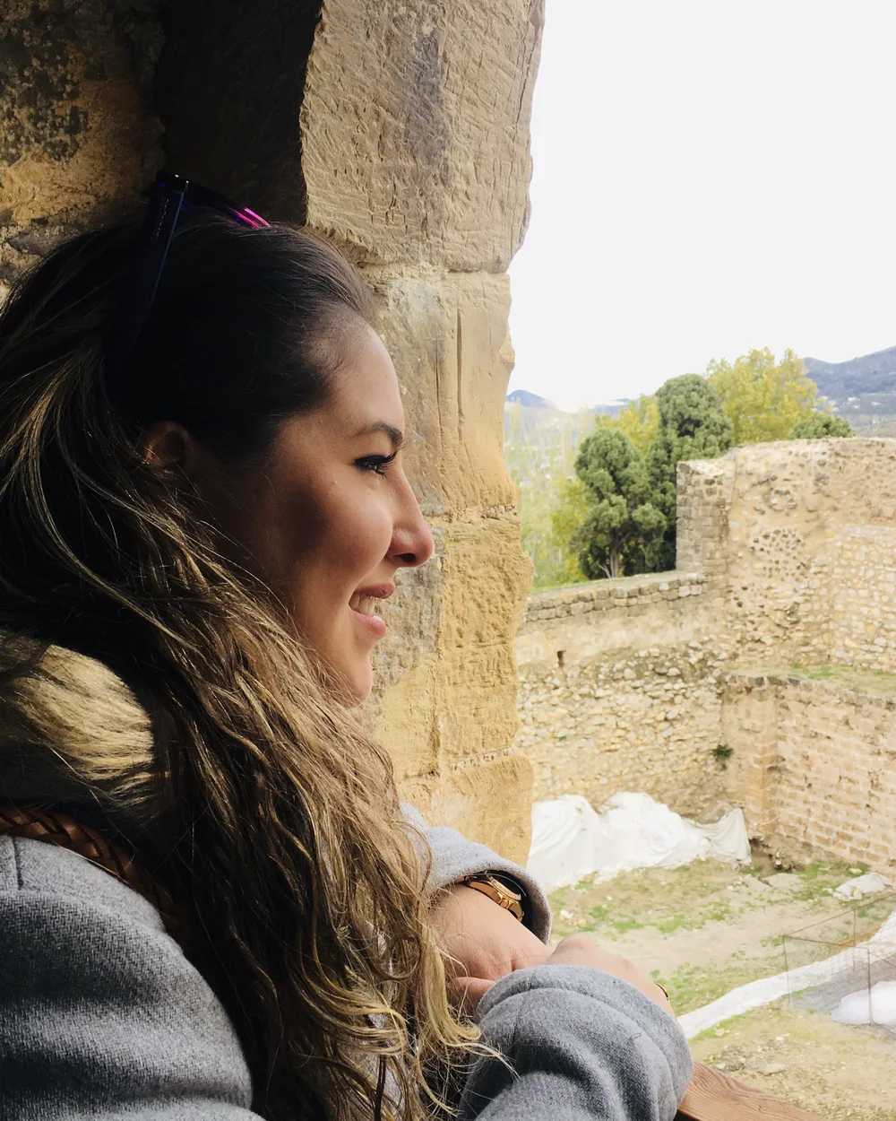 Cris sonriendo mientras mira por una ventana de piedra