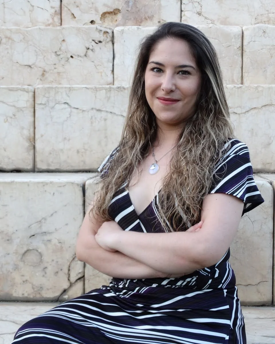 Cris con los brazos cruzados, apoyada de espaldas en un muro de piedra