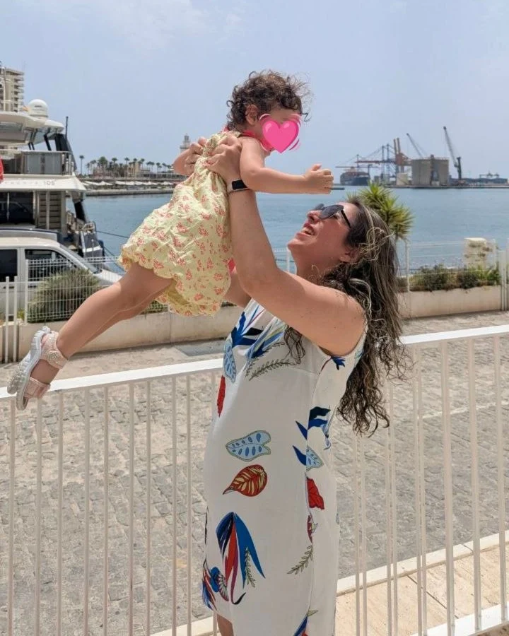 Cris Toledo levantando en brazos a su hija junto al mar