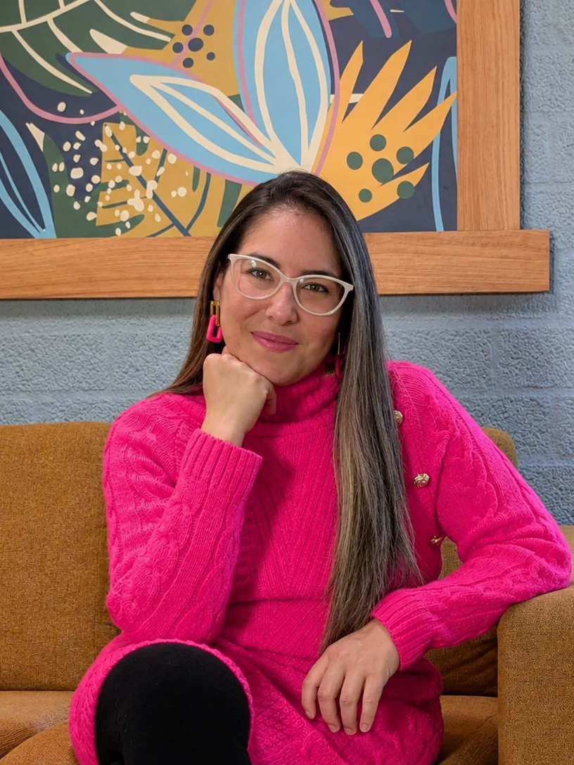 Cris con jersey rosa, la mano en la barbilla, sentada en un sofá