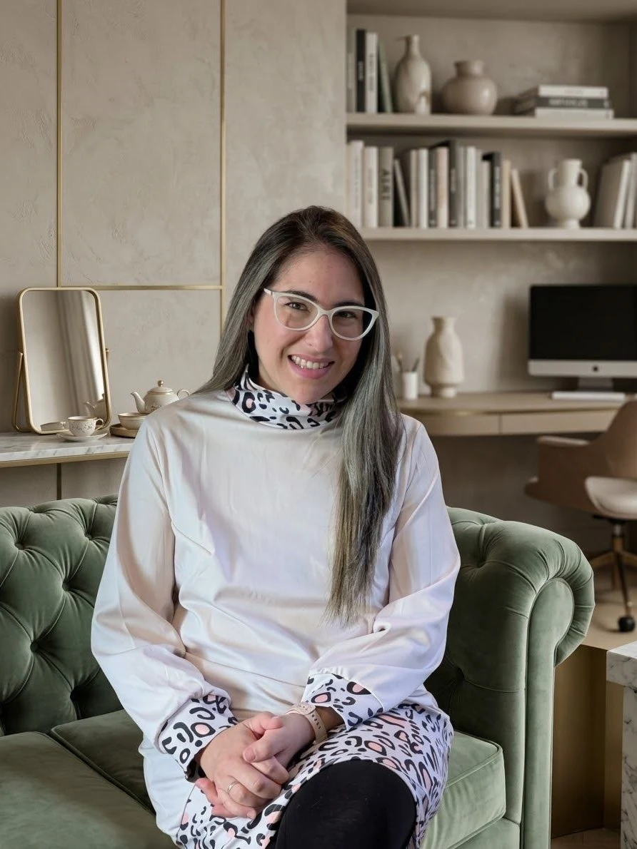 Cris Toledo sonriendo, sentada en un sofá verde de terciopelo